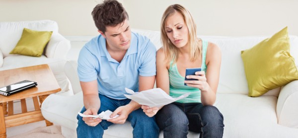 concentrated young couple calculating bills sitting on the sofa