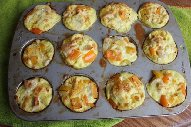 Golden baked egg muffins in a muffin tin with visible chunks of vegetables throughout. These individual protein packed breakfast bites are lightly browned on top and ready to serve.