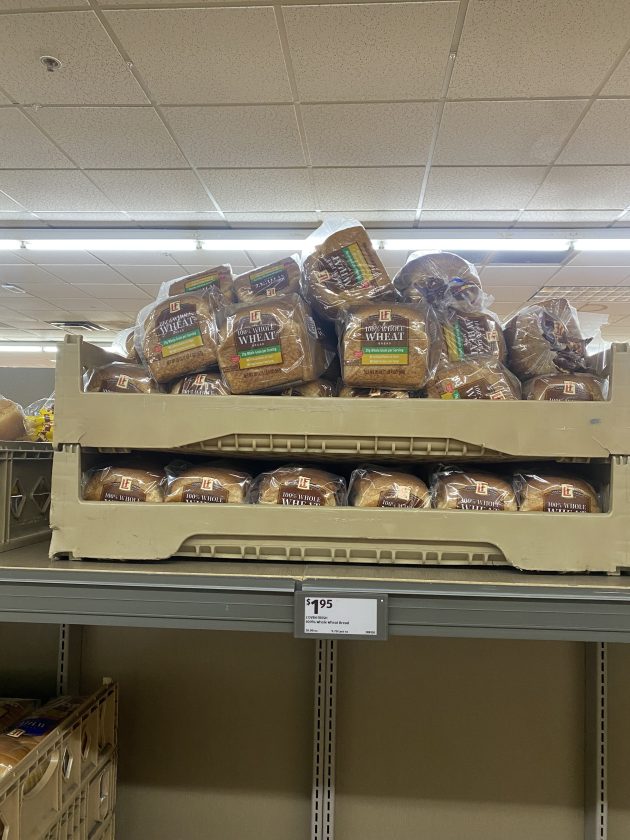 Large crate filled with loaves of bread labeled "100% Whole Wheat" stacked high.