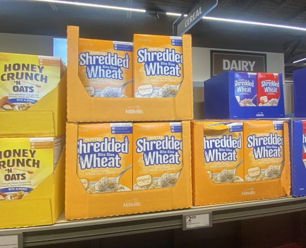 Boxes of cereal including "Honey Crunch n Oats" and "Frosted Shredded Wheat Bite Size Original" stacked on shelves with a price of "2.09".