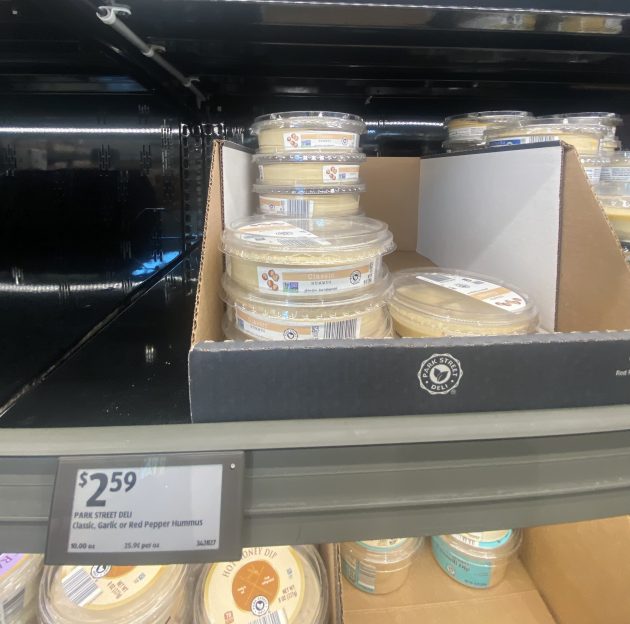 Open display of hummus containers labeled "Park Street Deli Classic Garlic" and "Red Pepper Hummus."