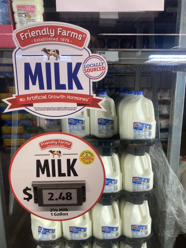 Refrigerator case filled with gallon jugs of milk.