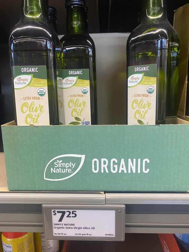 Bottles of "Simply Nature Organic Extra Virgin Olive Oil" arranged in a green box labeled "Simply Nature Organic" with a price tag of "7.25".
