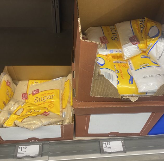 Bags of sugar labeled "Sugar" and "Light Brown Sugar" stacked in cardboard boxes.