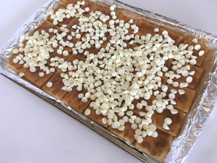 white chocolate chips on top of layered Easter candy in a pan