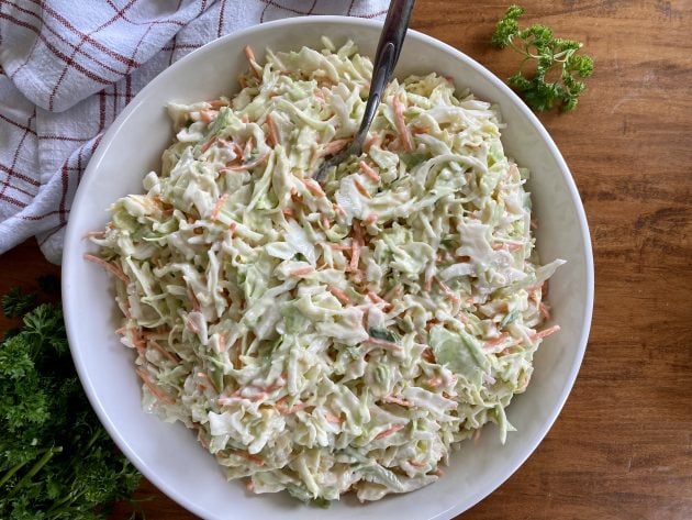 Creme de salada de repolho é servido em uma tigela com uma colher sobre a mesa