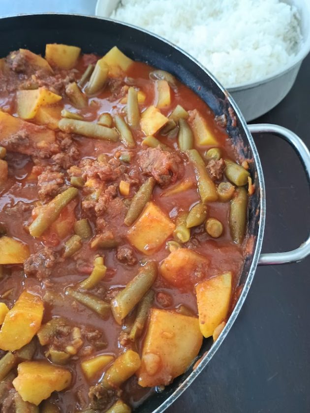 Close up of Pakistani kima showing minced meat, soft potatoes, and green beans coated in a thick spiced tomato sauce.