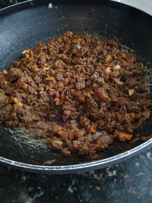 Cooked minced meat browned with chopped onions and spices in a frying pan, forming the base for Pakistani keema.