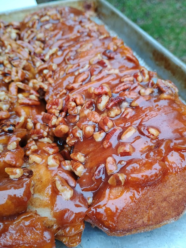 Finished monkey bread pulled apart and coated in caramel sauce with pecans on top