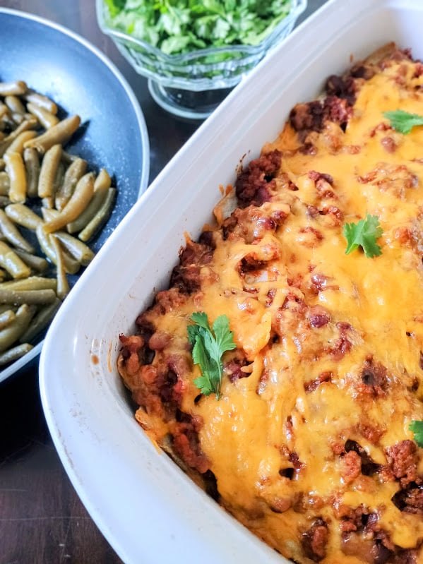 Close view of baked Mexican lasagna topped with melted cheddar cheese and cilantro.