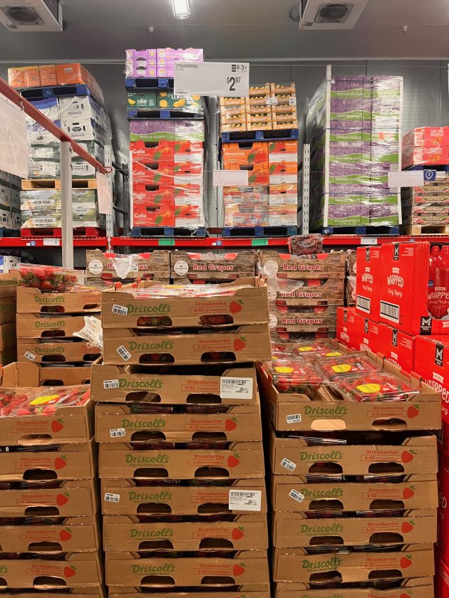 Repeated view of stacked Driscoll’s strawberry boxes and clamshell containers in bulk display with price signage above.