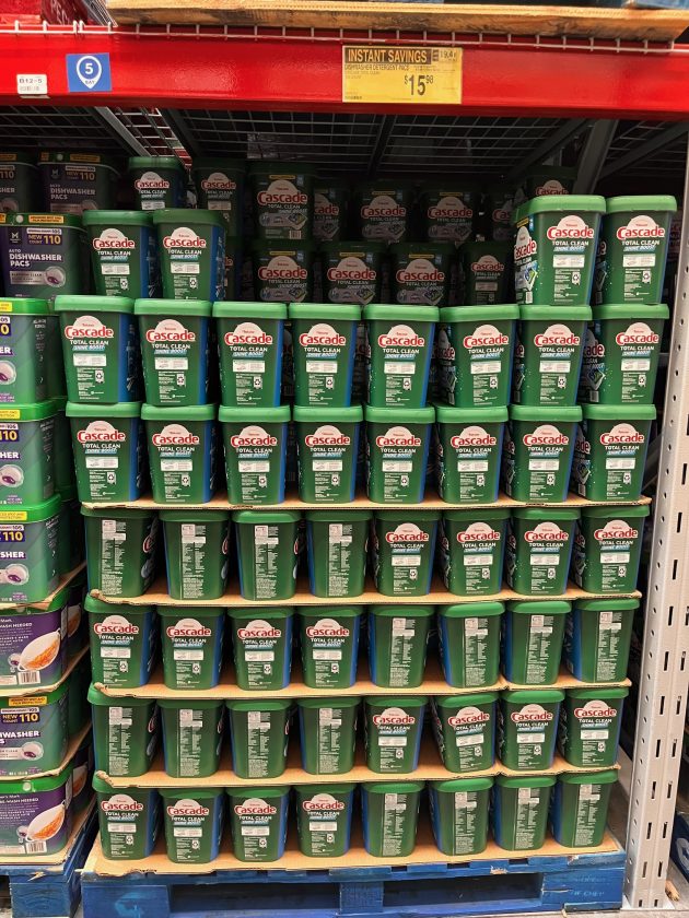 Pallet display of green containers labeled "Cascade TOTAL CLEAN" with a yellow sign above reading "INSTANT SAVINGS $15.98."