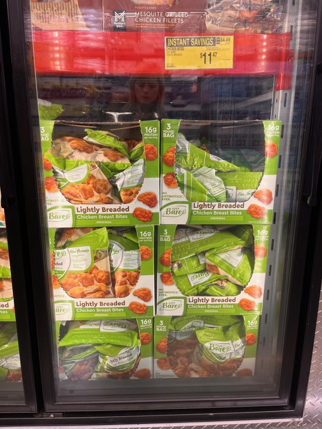 Freezer case filled with green bags labeled "Lightly Breaded Chicken Breast Bites" -- a must-have Sam's Club item -- with a yellow sign above reading "INSTANT SAVINGS $11.47."