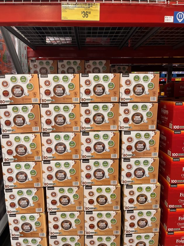 Pallet stacked display of purple boxes labeled "POWER FLEX 200 Tall Kitchen Bags" with price signage hanging above.