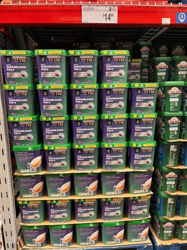 Shelf stocked with containers labeled "AUTO DISHWASHER PACS" with text "NEW 110" and a price sign above reading "$14.98."