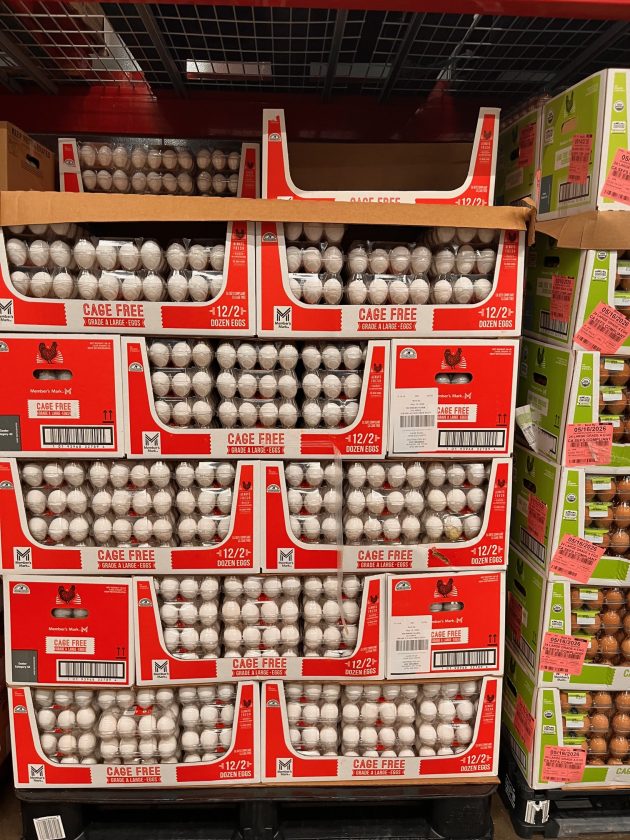 Bulk display of cartons labeled "CAGE FREE Grade A large eggs" stacked in large quantities on warehouse shelves.