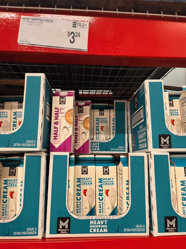 Shelf of cartons labeled "HEAVY WHIPPING CREAM" and "HALF & HALF" in teal and pink packaging with a price sign reading "$3.24" above the display.