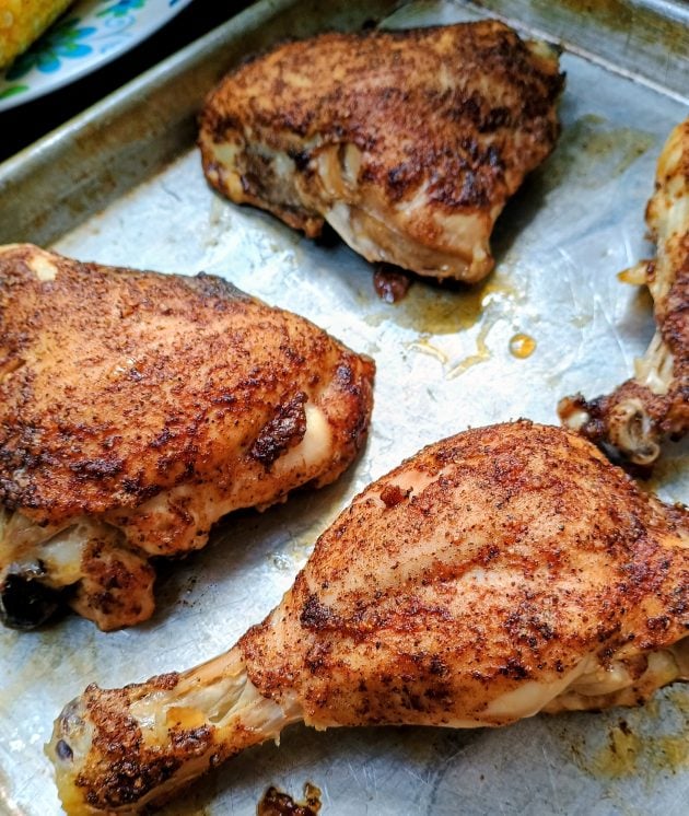Golden brown baked chicken leg quarters and drumsticks resting on a baking sheet.