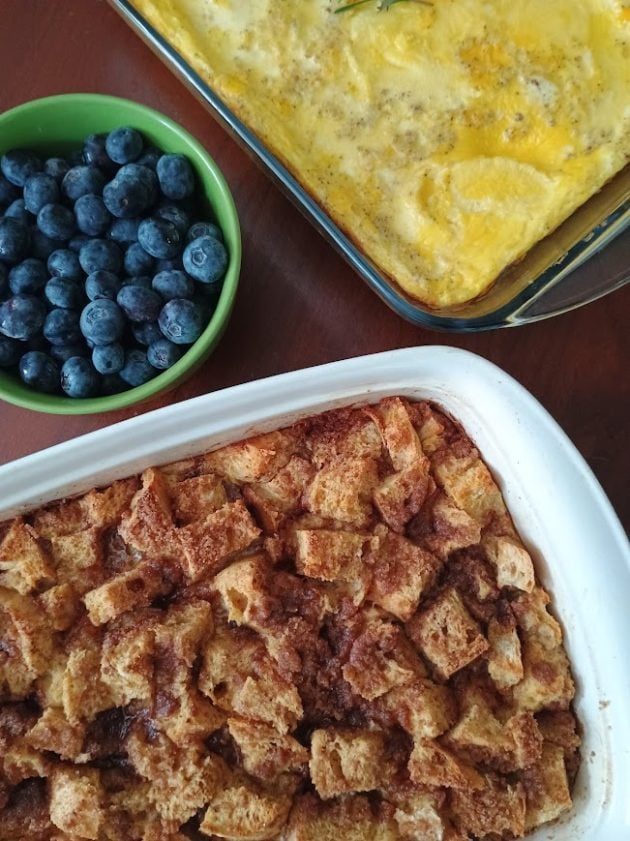 Finished French toast casserole served with baked scrambled eggs and a bowl of fresh blueberries.