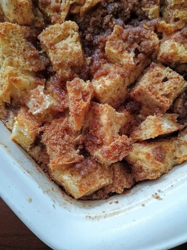Close up of a baked French toast casserole with golden brown bread cubes and a cinnamon sugar topping.