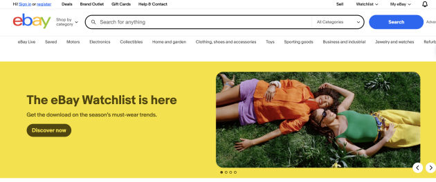 eBay homepage featuring a bright yellow banner promoting the Watchlist feature alongside two people lying on the grass.