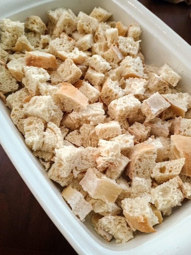 Cubes of bread arranged in a white baking dish.