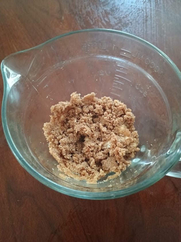 Brown sugar and butter crumble topping mixed in a glass measuring cup for a French toast casserole.