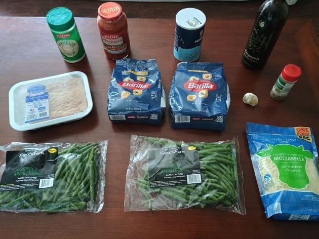 Ingredients for tortellini bake and green beans arranged on a table.
