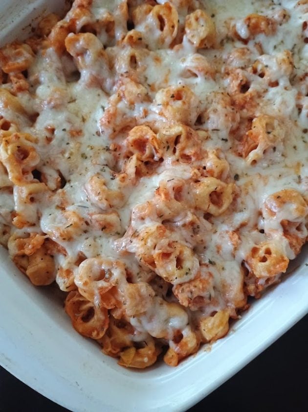 Cheesy baked tortellini in tomato sauce topped with melted cheese and herbs.