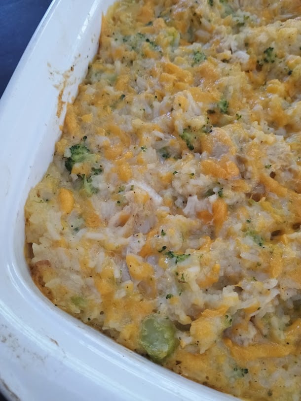 Close view of baked chicken broccoli rice casserole topped with melted cheddar cheese.